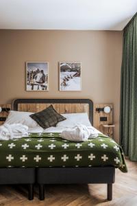 a bedroom with a bed with a green blanket on it at Faern Crans-Montana Valaisia in Crans-Montana