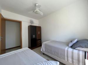 een slaapkamer met 2 bedden en een zwarte kast bij Apartamento 2 quartos completo 200 m da praia in Capão da Canoa