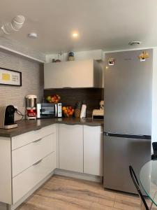 a kitchen with white cabinets and a stainless steel refrigerator at Convivialetzen in Châtenoy-le-Royal