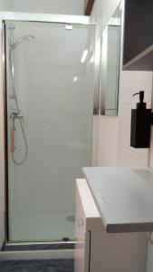 a white bathroom with a shower and a sink at Le Relais de Jeanne in Orbigny