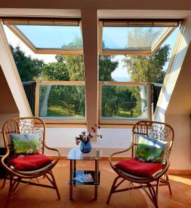 two chairs and a table in a room with windows at Traumblick und Komfort - lichtdurchflutete 85 qm Wohnung nahe Südstrand Göhren inklusive Schwimmbad und Sauna im AHOI Sellin in Göhren