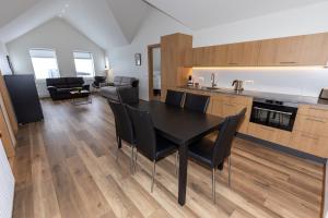 a kitchen and dining room with a black table and chairs at Hrimland Guesthouse in Akureyri