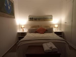 a bedroom with a bed with two lamps and towels on it at Dormir entre limones, Casa de invitados en vivienda familiar in Dos Hermanas