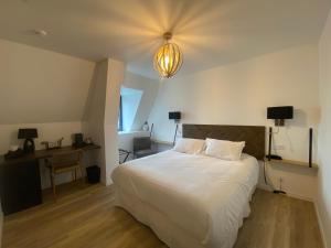a bedroom with a large white bed and a lamp at LA TOUR AUX CRABES près de la plage in Dieppe