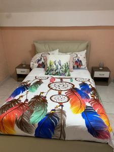 een bed met een kleurrijke deken met pauwenveren erop bij Villa Sophie in SantʼAgata di Militello