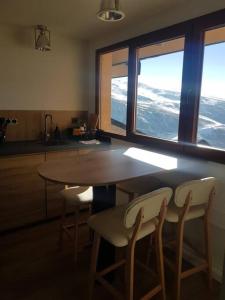 a kitchen with a table and two chairs and two windows at ¡A pie de pistas! in Monachil