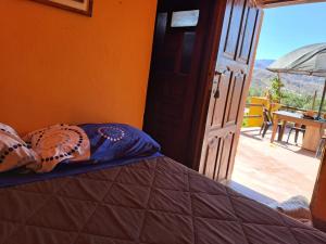Cama en habitación con puerta abierta en Carnavalito Hostel Tilcara en Tilcara