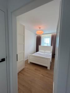 a bedroom with a white bed and a window at Apartament Nowe Ogrody in Leszno