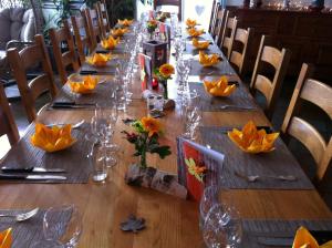 a long wooden table with glasses and flowers on it at Chambres d'hôtes Chez Epicure in Ballaigues