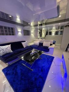 sala de estar con muebles azules y mesa de cristal en Chambre de luxe familiale 95 Bleu, en Deuil-la-Barre