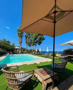 - une piscine avec 2 chaises et un parasol dans l'établissement Residence VILLA MOROSI - Favone, à Conca