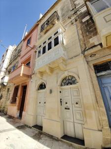 an old building with two white doors on a street at Crew 2 Savynomad Harbour Residences wow Views in Cospicua