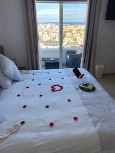 a bed with red roses on it with a window at Escape to St Julians in St Julian's