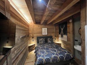 1 dormitorio con paredes de madera, 1 cama y lavamanos en Appartement haut standing Arêches beaufort, en Arêches