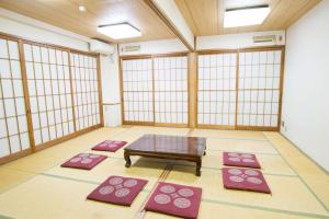 a room with a table and four mats at 駅前山小屋A-yard in Ome