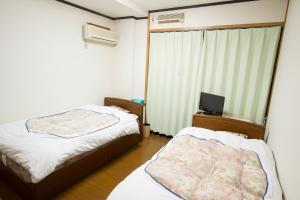 Habitación pequeña con 2 camas y TV. en 駅前山小屋A-yard, en Ome