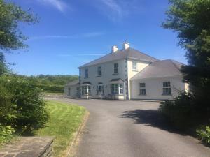 a large white house with a driveway at Dromkeal View Apartment in Cork