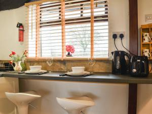 a kitchen counter with two white stools and a window at The Snug - Uk42088 in Sedbergh