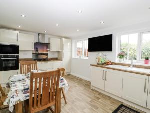 a kitchen with white cabinets and a table with chairs at 8A Rosewood Avenue in Burnham on Sea