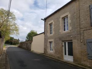 an empty street next to a brick building at Maison chaleureuse entre mer et campagne in Colombiers-sur-Seulles