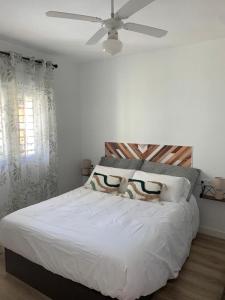 a bedroom with a white bed with a ceiling fan at Apartamento Peñas Blancas, junto a ruta de los Cahorros, Monachil. in Monachil