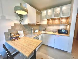 a kitchen with white cabinets and a wooden table at Marina Garden in Budapest