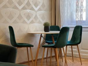 stół z czterema zielonymi krzesłami i doniczką w obiekcie N38 Apartments by Small Home Budapest w Budapeszcie