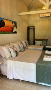 uma cama grande com almofadas num quarto em Pousada Preciosa do Arraial - com Natura e L'Occitane -inaugurada há 1 ano em Arraial d'Ajuda