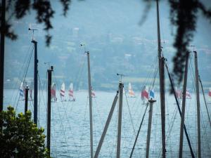 a group of sailboats in the water with flags at Albergo Lario in Gera Lario