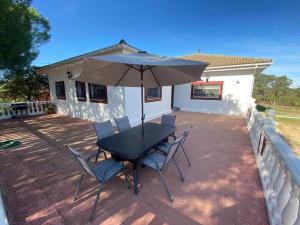 a table and chairs with an umbrella on a patio at CHALET con ENCANTO en SIERRA CORDOBESA. WIFI in Cerro Muriano