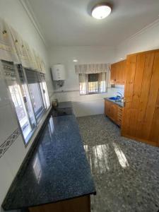 a large kitchen with a counter top and wooden cabinets at CHALET con ENCANTO en SIERRA CORDOBESA. WIFI in Cerro Muriano
