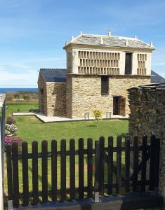a large stone building behind a wooden fence at "O Cabazo de Reinante" in Barreiros