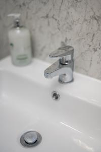 - un lavabo avec robinet et une bouteille de savon dans l'établissement The School House, à Broughty Ferry