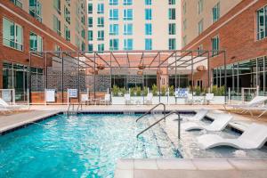 a swimming pool with chairs and a building at Residence Inn by Marriott Greenville Downtown in Greenville