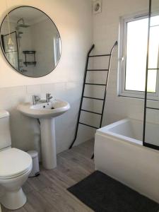 a bathroom with a sink and a toilet and a mirror at Fresh 4 Bed Coastal Home nr Padstow in Padstow
