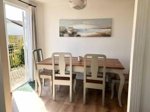 a dining room table with two chairs and a painting on the wall at Fresh 4 Bed Coastal Home nr Padstow in Padstow