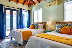 two beds in a room with blue curtains at Jost Van Dyke, BVI 3 Bedroom Villa with Caribbean Views & Pool in Jost Van Dyke