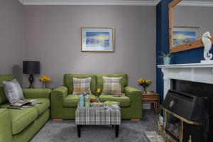 a living room with two green couches and a fireplace at The Elderton, Newbiggin By The Sea, Northumberland in Newbiggin-by-the-Sea
