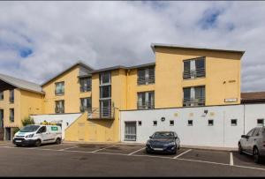 dos autos estacionados en un estacionamiento frente a un edificio en Stunning 3 bed seaview apartment, en Musselburgh