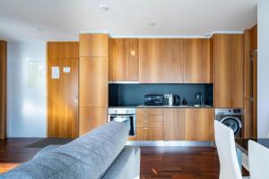 una cocina con armarios de madera y un sofá en una habitación en Manu&Noa, en A Illa de Arousa