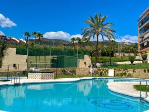 een groot blauw zwembad met palmbomen en een gebouw bij Hevres Playa Torremolinos in Torremolinos