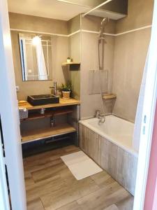 La salle de bains est pourvue d'une baignoire et d'un lavabo. dans l'établissement LE COSY plein centre avec terrasse, à Meximieux