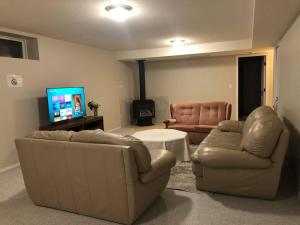 a living room with two couches and a flat screen tv at Licensed spacious basement suite with two king size beds in Chilliwack