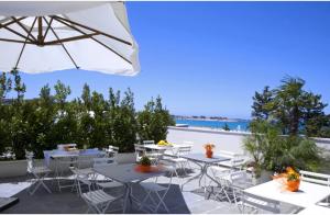a patio with tables and chairs and an umbrella at Le Stelle Sea Rooms in San Vito lo Capo