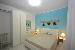a bedroom with a white bed and a mirror at Le Stelle Sea Rooms in San Vito lo Capo