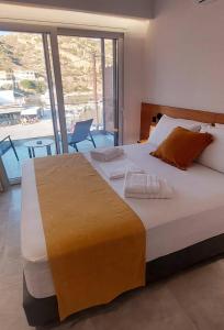 duże łóżko w sypialni z dużym oknem w obiekcie Amimaya Apartments w mieście Emporeiós