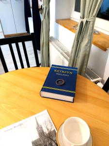 a blue book sitting on top of a wooden table at Apartament Kętrzyński in Kętrzyn