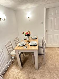 a dining room table with chairs and flowers on it at Mount Yard - Stylish Cottage - Close to Alton Towers - Water World -Stoke-on-Trent Sleeps 5 in Totmonslow