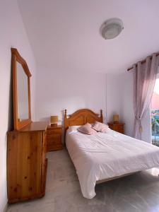 a bedroom with a bed and a dresser and a mirror at Los Hidalgos Golf 7 in Manilva
