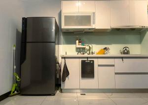 una cocina con nevera de acero inoxidable y armarios blancos en 慢時光中興時尚青公寓, en Nantou City